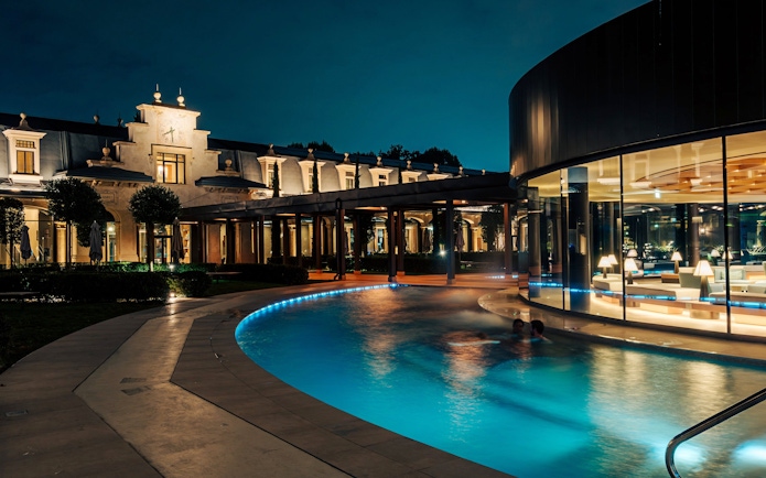 Milan spa with illuminated pool and elegant architecture at night.