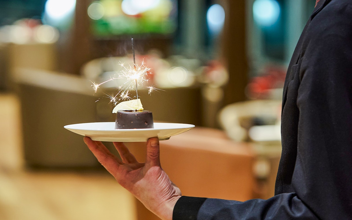 Waiter serving dessert with sparkler on Paris En Scène Dinner Cruise, Seine River.