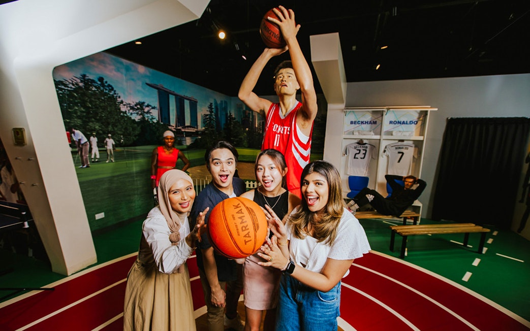 Visitors interacting with Yao Ming wax figure at Madame Tussauds Singapore.