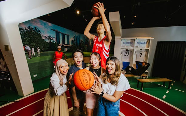 Visitors interacting with Yao Ming wax figure at Madame Tussauds Singapore.