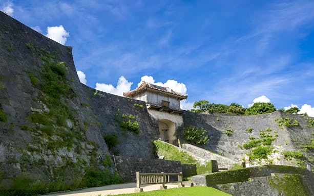Shurijo Castle Park stone walls and gate under a blue sky in Okinawa, Japan.