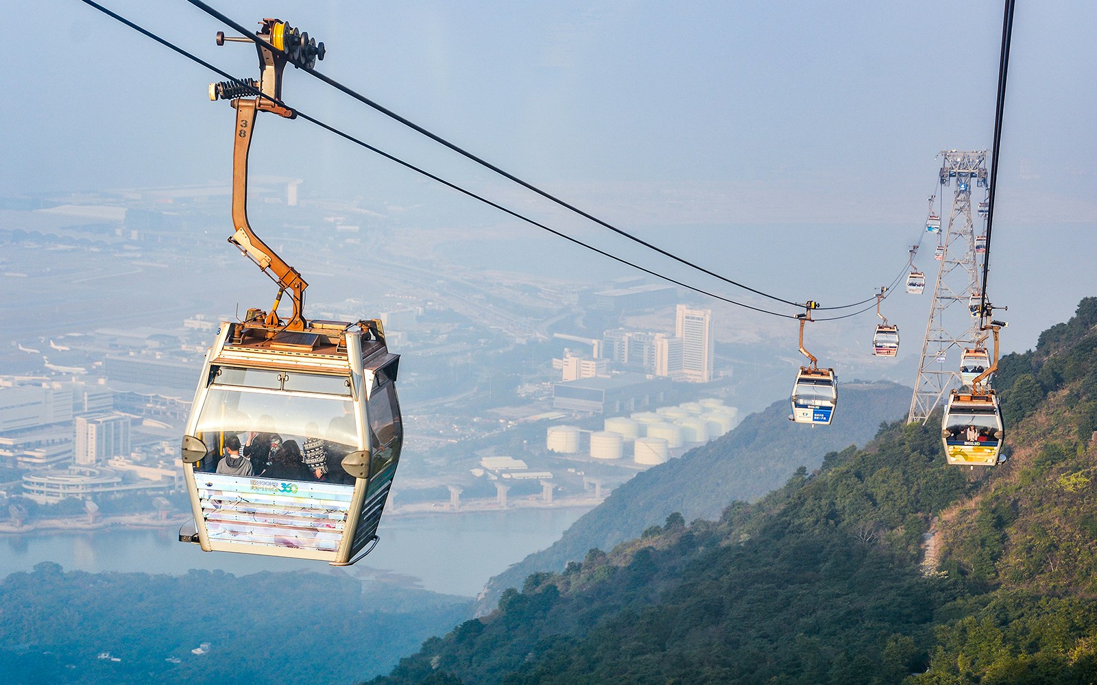 Ngong Ping Cable Car over Lantau Island, Hong Kong, with cityscape view.