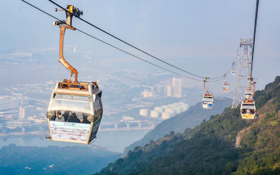 Ngong Ping Cable Car over Lantau Island, Hong Kong, with cityscape view.