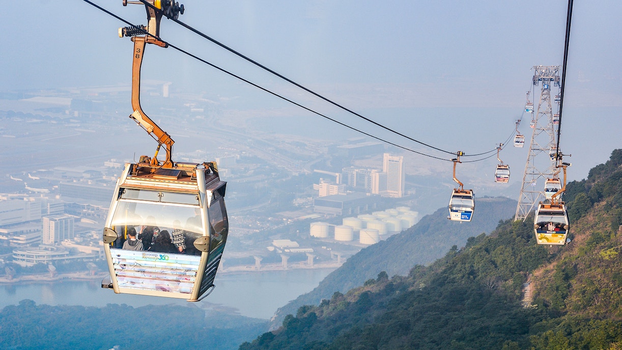 Ngong Ping Cable Car over Lantau Island, Hong Kong, with cityscape view.