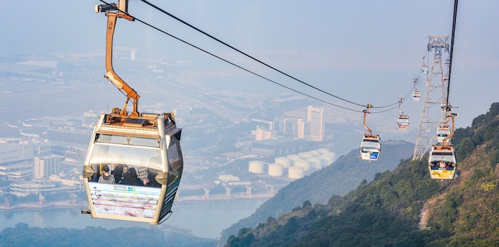 Ngong Ping Cable Car over Lantau Island, Hong Kong, with cityscape view.