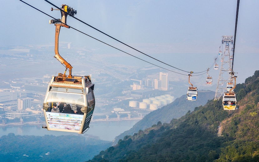 Ngong Ping Cable Car over Lantau Island, Hong Kong, with cityscape view.