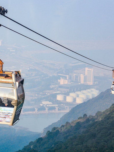 Ngong Ping Cable Car over Lantau Island, Hong Kong, with cityscape view.