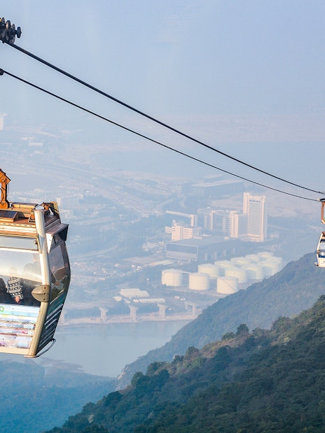 Ngong Ping Cable Car over Lantau Island, Hong Kong, with cityscape view.