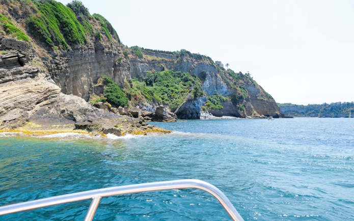 Boat view of rocky coastline and cliffs on Procida Island tour.