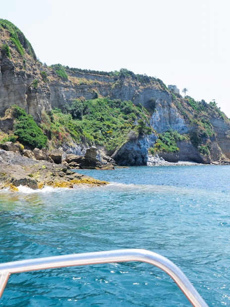 Boat view of rocky coastline and cliffs on Procida Island tour.