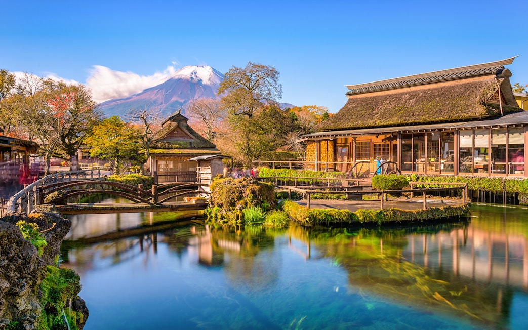 Traditional buildings and pond at Oshino Hakkai Village, Japan, with Mount Fuji in the background.
