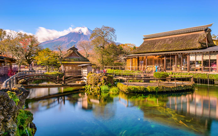 Traditional buildings and pond at Oshino Hakkai Village, Japan, with Mount Fuji in the background.