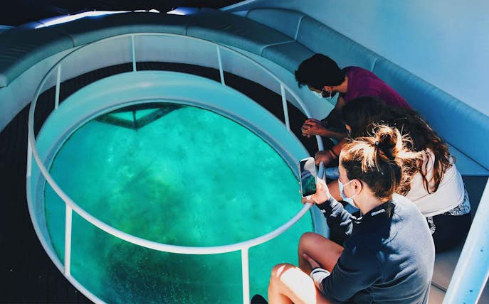 Visitors observing marine life through a glass bottom boat in São Miguel.