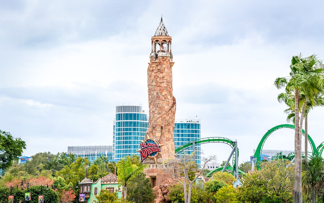 Islands of Adventure lighthouse at Universal Studios Resort, Orlando, with roller coaster in background.