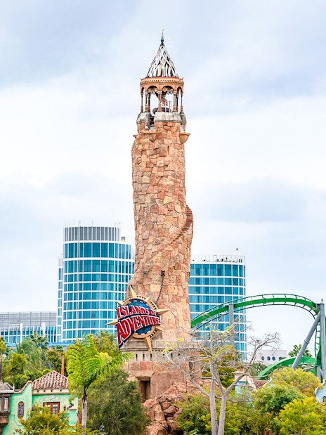 Islands of Adventure lighthouse at Universal Studios Resort, Orlando, with roller coaster in background.