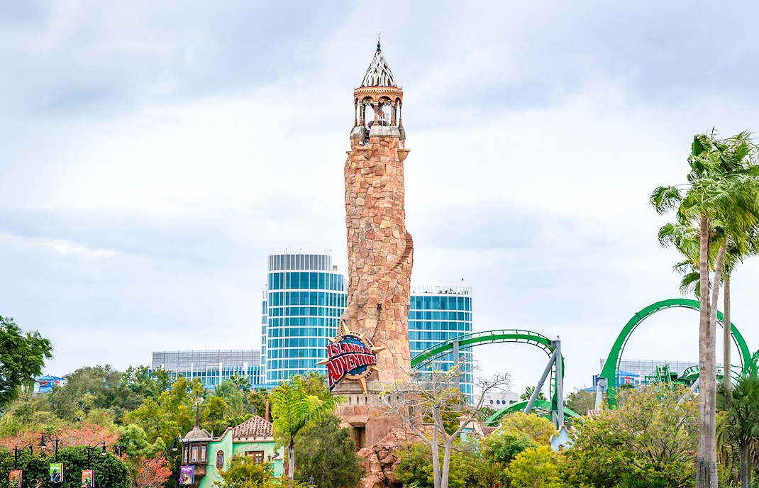 Islands of Adventure lighthouse at Universal Studios Resort, Orlando, with roller coaster in background.