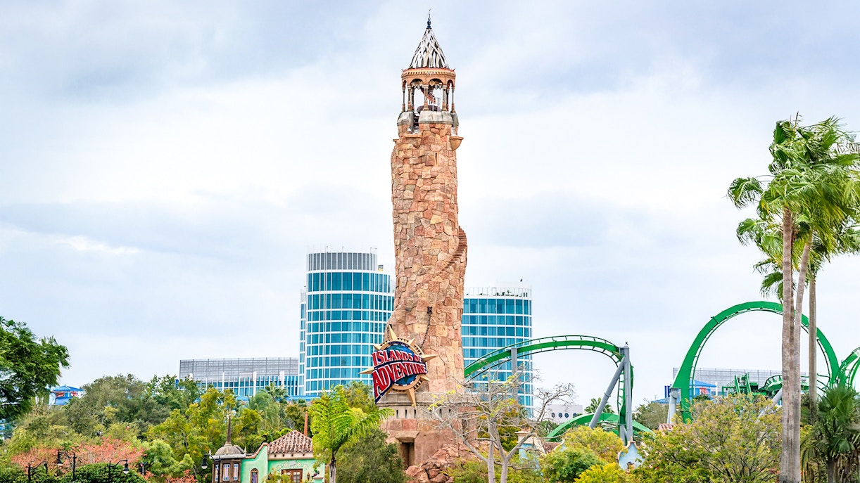 Islands of Adventure lighthouse at Universal Studios Resort, Orlando, with roller coaster in background.