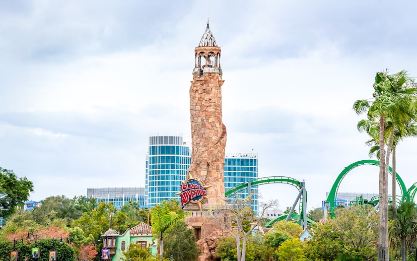 Islands of Adventure lighthouse at Universal Studios Resort, Orlando, with roller coaster in background.