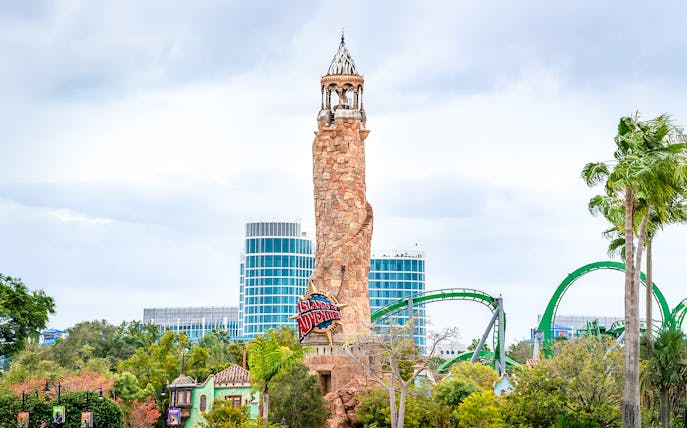 Islands of Adventure lighthouse at Universal Studios Resort, Orlando, with roller coaster in background.