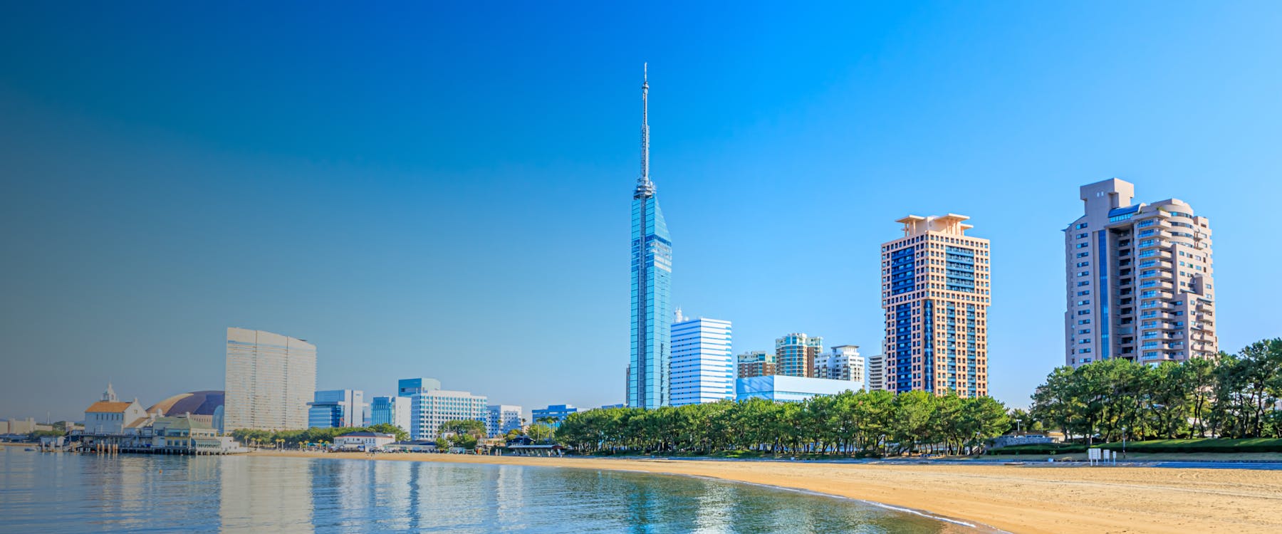 Fukuoka skyline with Fukuoka Tower and beach in the foreground.