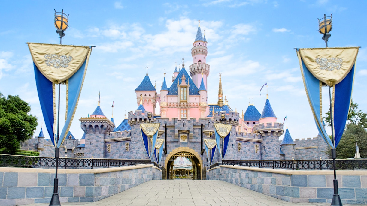 Disney Castle at Disneyland Park, California with blue and gold banners.