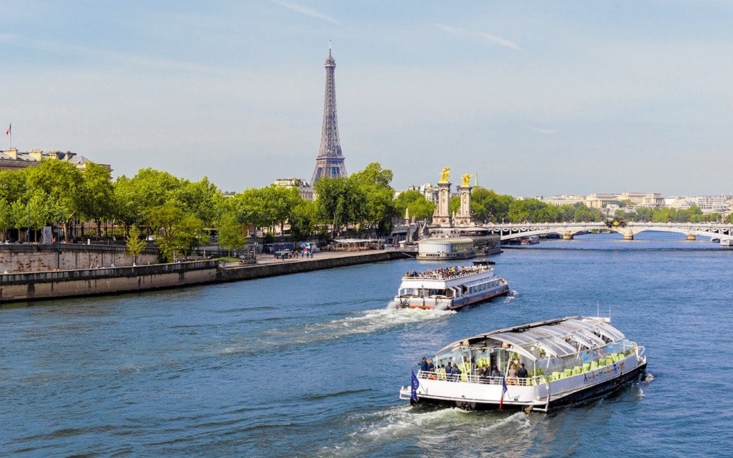 Seine River cruise boats with Eiffel Tower and Pont Alexandre III in Paris.