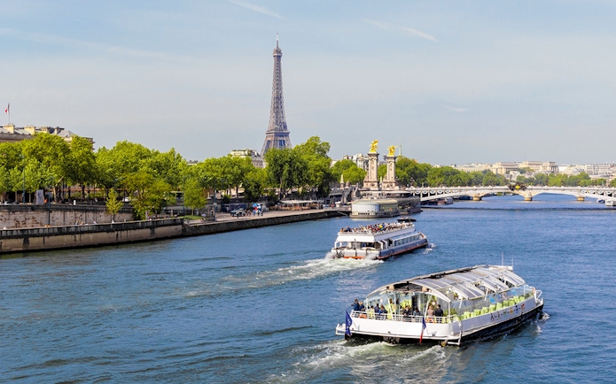 Seine River cruise boats with Eiffel Tower and Pont Alexandre III in Paris.