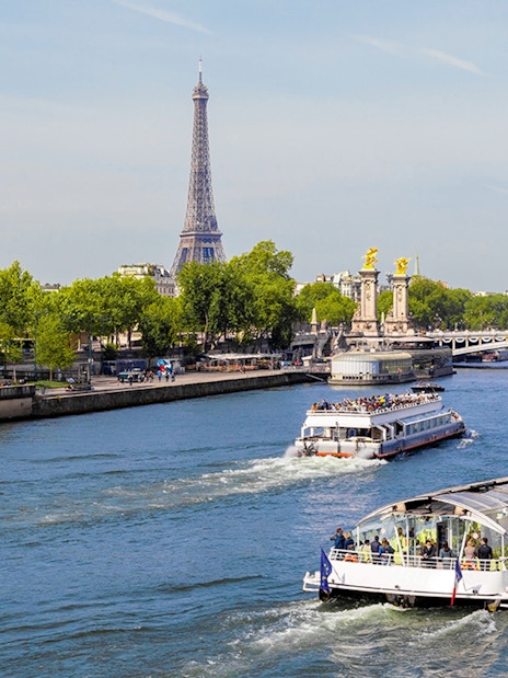 Seine River cruise boats with Eiffel Tower and Pont Alexandre III in Paris.