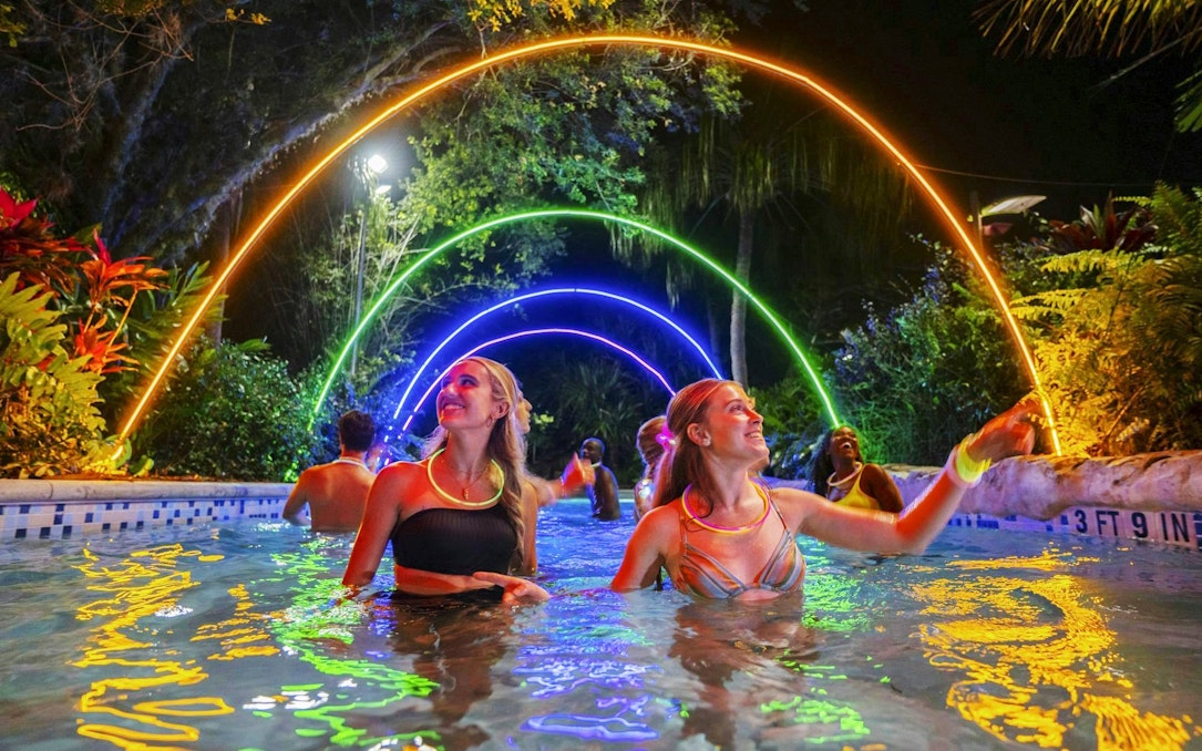 Guests enjoying AquaGlow event at Aquatica San Antonio under colorful illuminated arches.