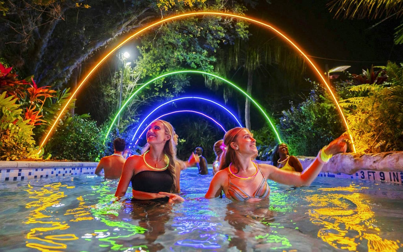 Guests enjoying AquaGlow event at Aquatica San Antonio under colorful illuminated arches.