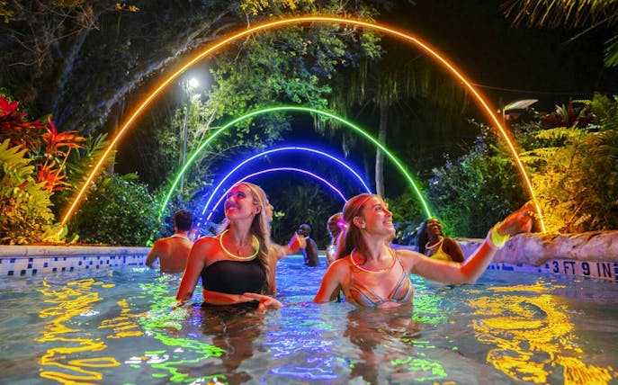 Guests enjoying AquaGlow event at Aquatica San Antonio under colorful illuminated arches.