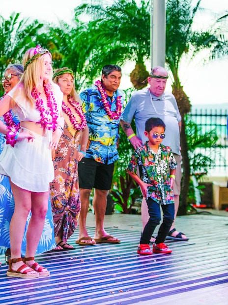 Guests participating in a dance at a traditional Hawaiian luau at Moana Luau, Hawaii.