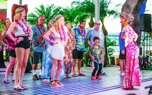 Guests participating in a dance at a traditional Hawaiian luau at Moana Luau, Hawaii.