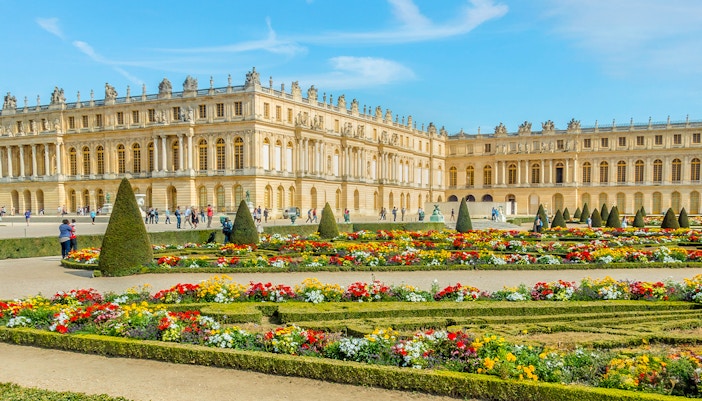 Palace of Versailles with garden view, showcasing ornate architecture and expansive landscaped gardens in France.