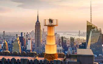 Couple enjoying sunset view from Top of the Rock, New York City skyline in background.