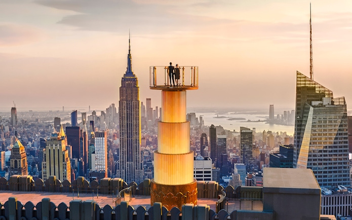 Couple enjoying sunset view from Top of the Rock, New York City skyline in background.