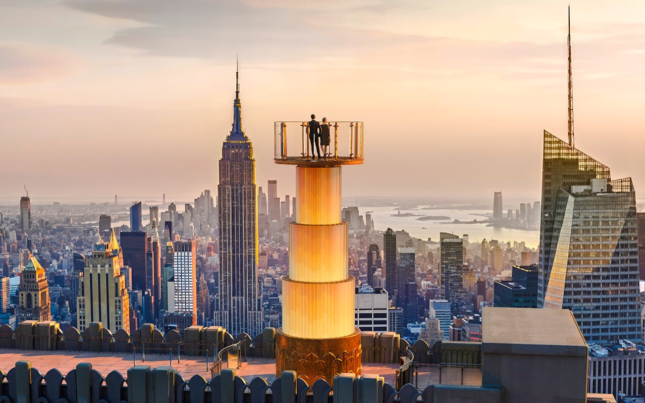 Couple enjoying sunset view from Top of the Rock, New York City skyline in background.