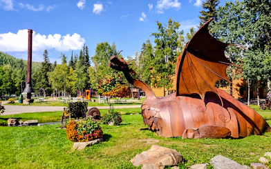 Metal dragon sculpture at Chena Hot Springs with surrounding greenery and picnic area.