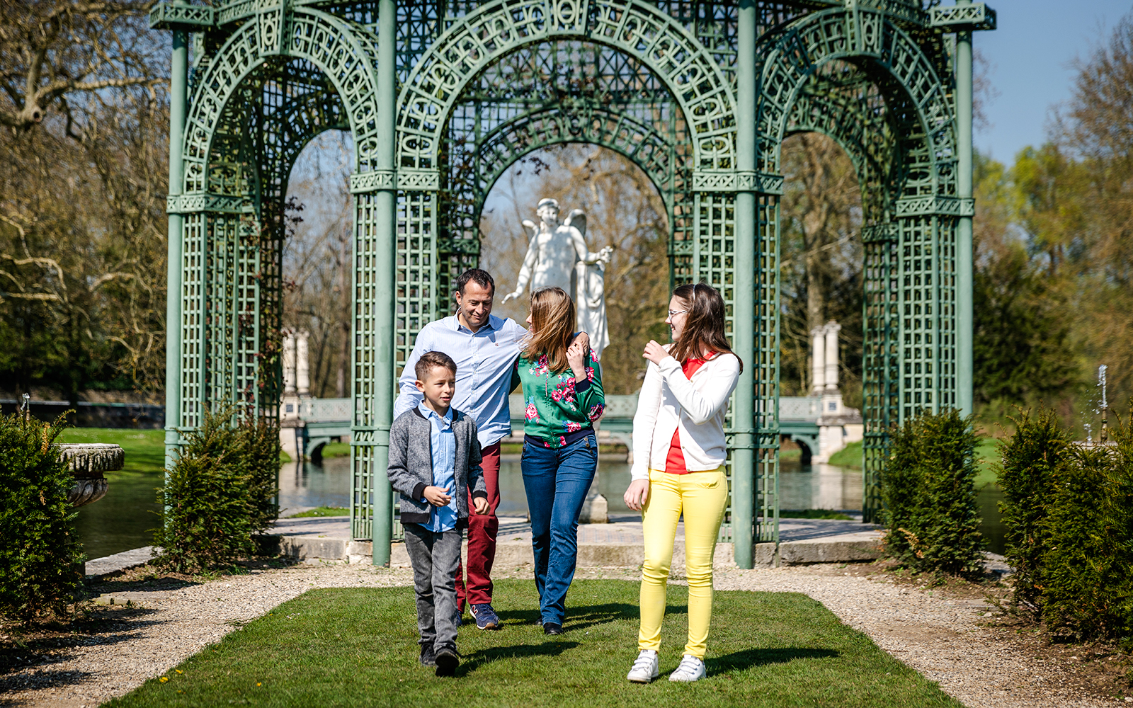 Family walking in the gardens of Chateau of Chantilly, France.