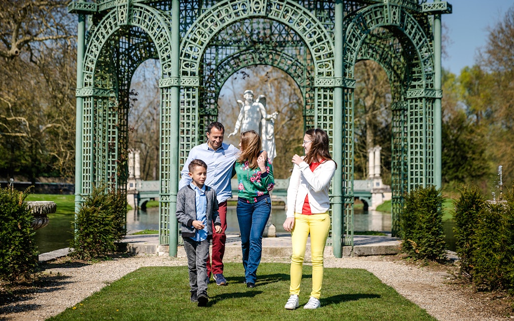 Family walking in the gardens of Chateau of Chantilly, France.