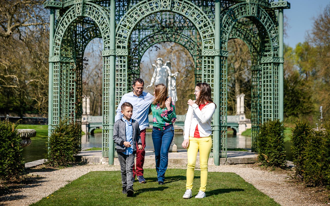 Family walking in the gardens of Chateau of Chantilly, France.