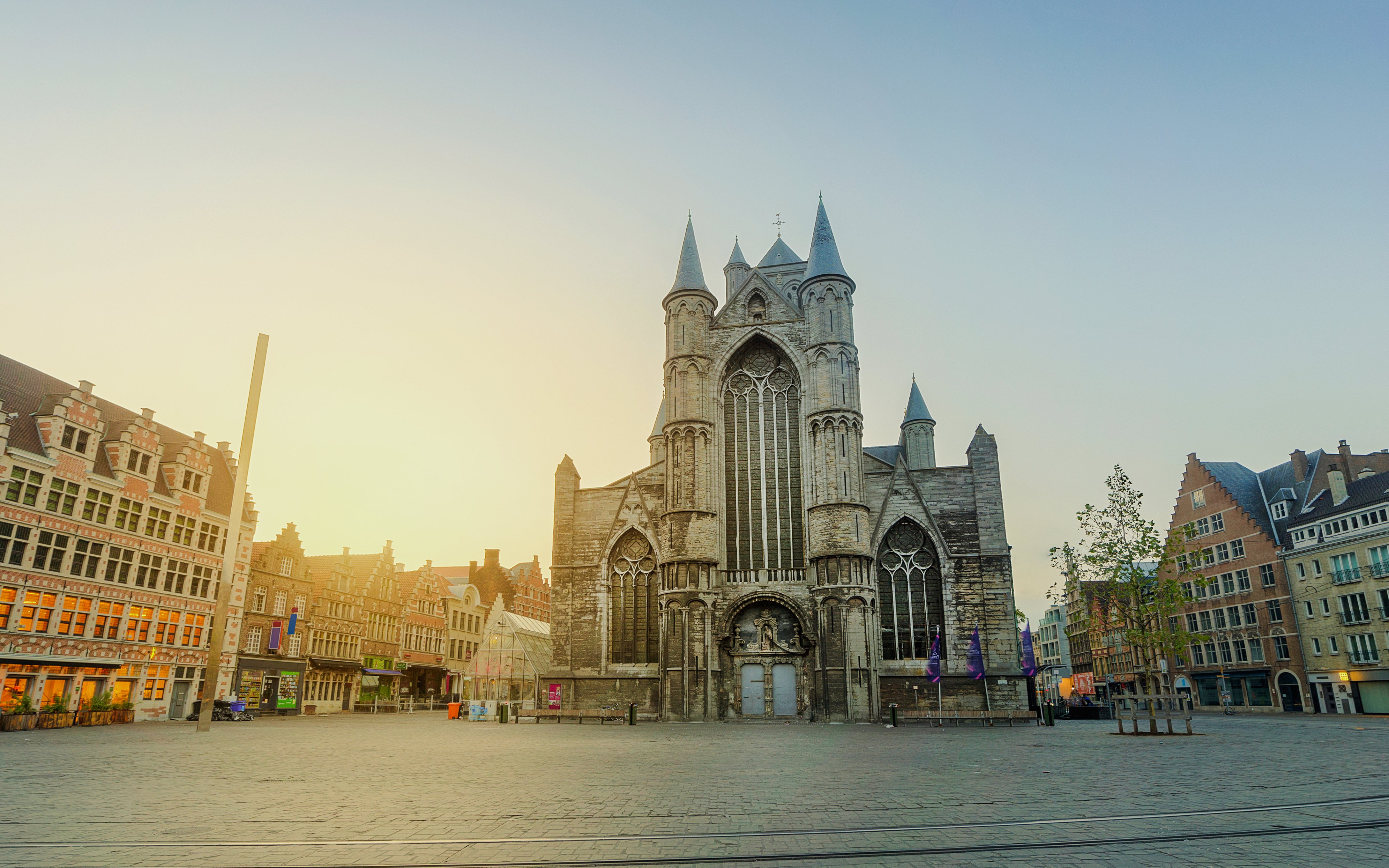 Saint Nicholas Church in Ghent, Belgium, with surrounding historic buildings at sunset.