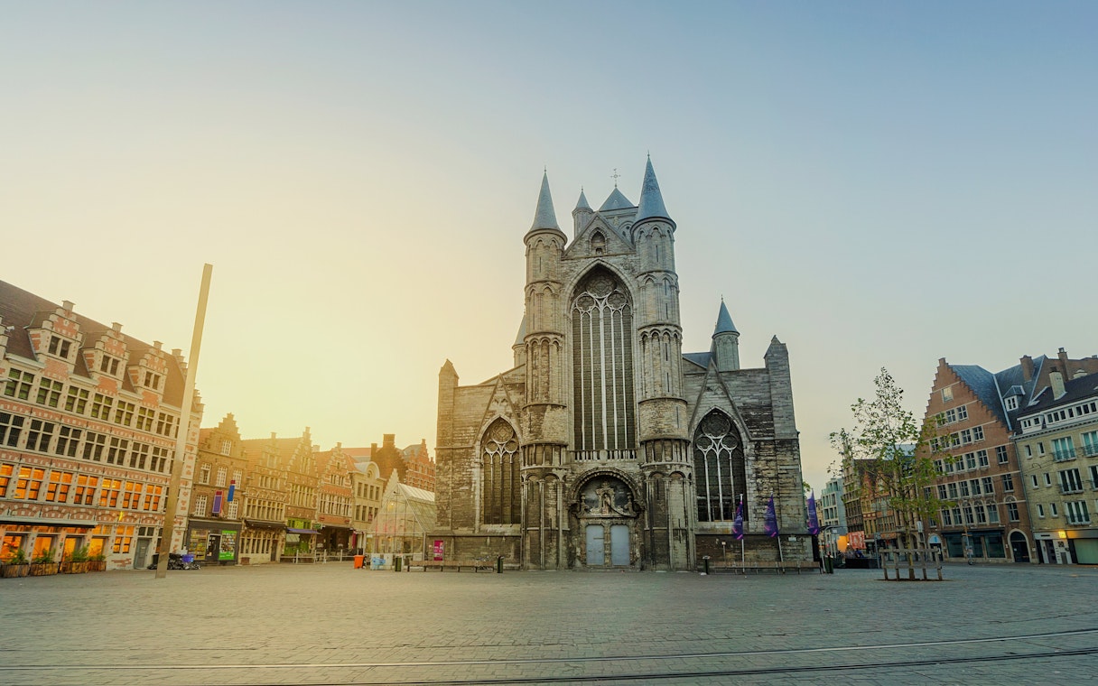 Saint Nicholas Church in Ghent, Belgium, with surrounding historic buildings at sunset.
