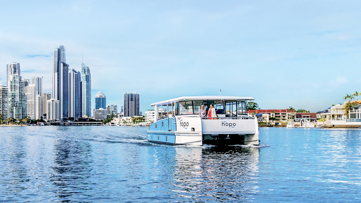 Hop On Hop Off Cruise on Gold Coast waterway with city skyline in background.