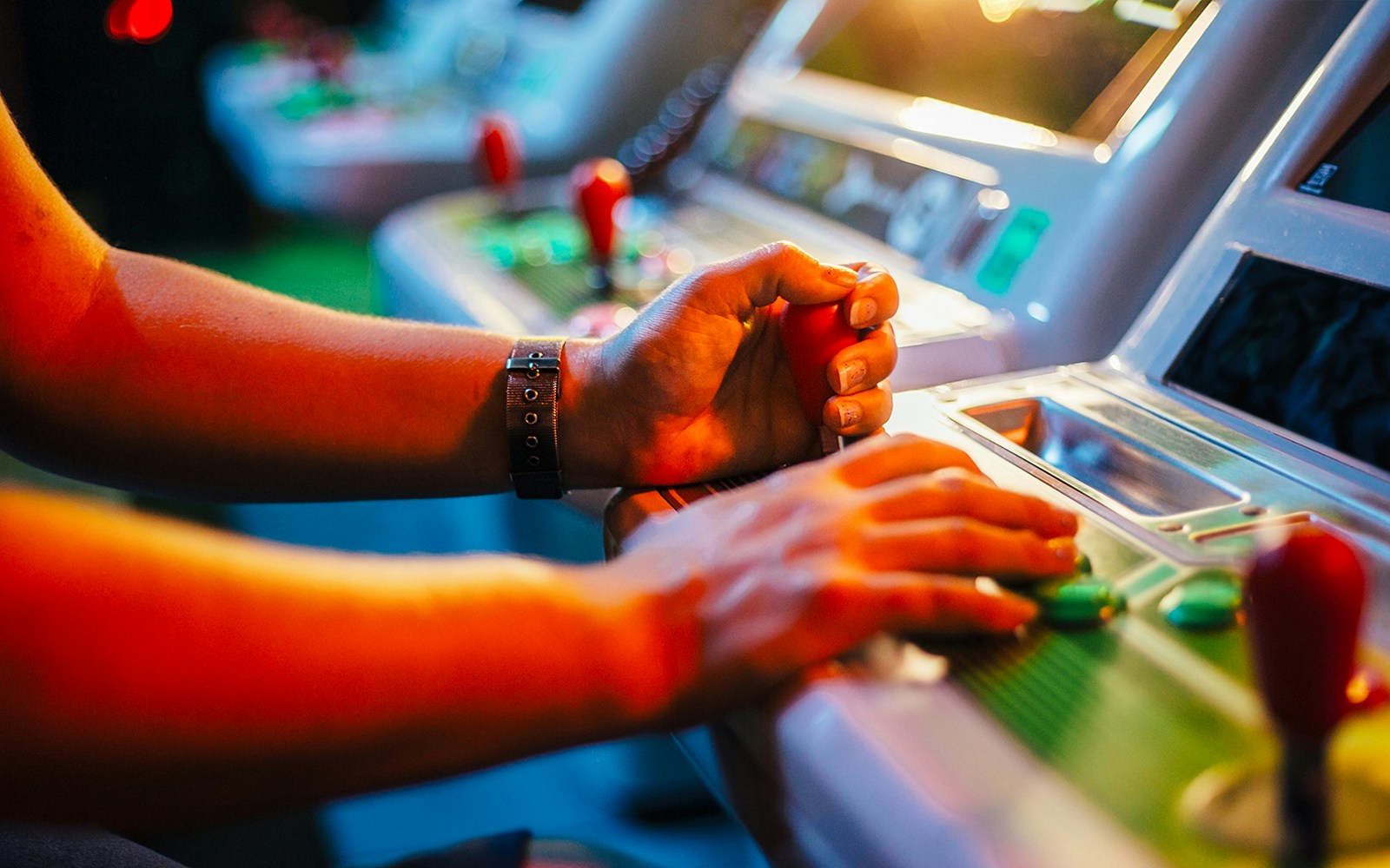Hands playing on an arcade machine in a gaming center.