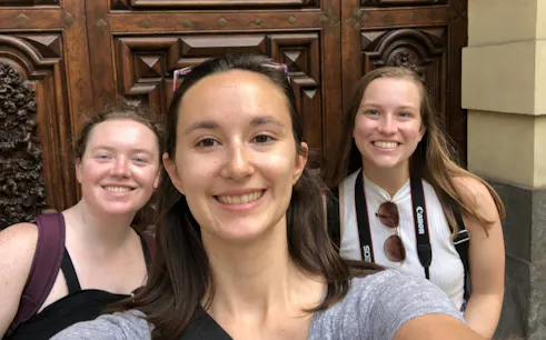 Three people smiling in front of ornate wooden doors in Turin during a self-guided city exploration game.