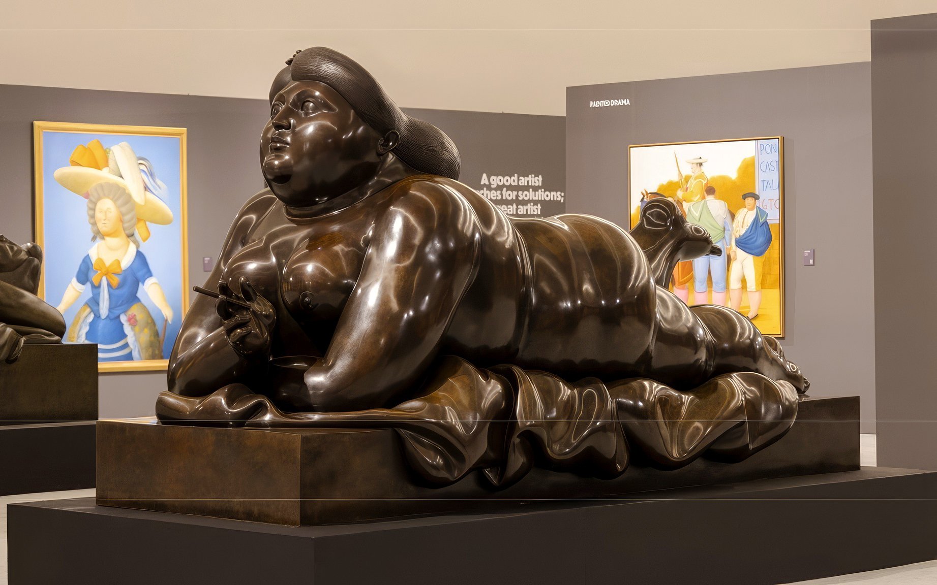 Sculpture of a reclining figure in Boterismo style at an art gallery.