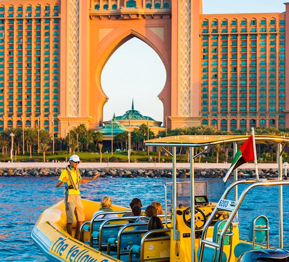 Yellow boat tour near Atlantis Hotel, Dubai, with guide and passengers on board.