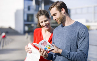 Tourists reading the Berlin Welcome Card by a city landmark.