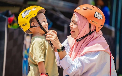 Woman adjusting child's helmet at The Skyline Luge, Kuala Lumpur.